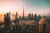 A breathtaking view of Dubai's skyline during sunset, featuring iconic skyscrapers including the Burj Khalifa, with busy roadways and construction in the foreground.