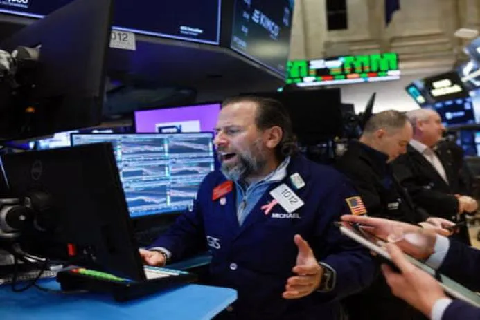 A Wall Street trader passionately reacting while working at his computer during trading hours.