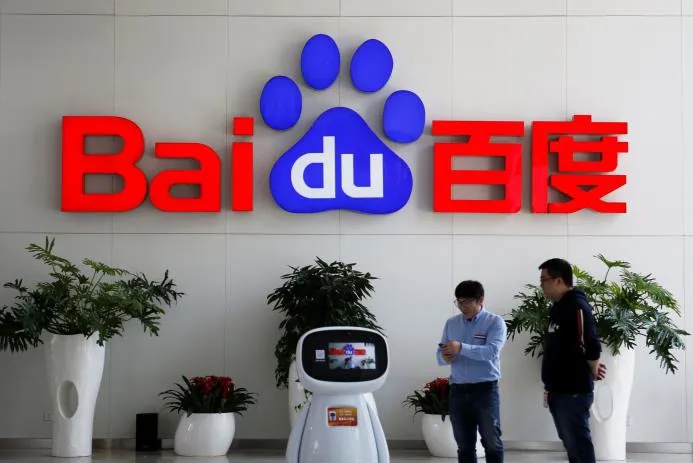 Baidu office signage with the logo and two employees interacting in front of a plant.