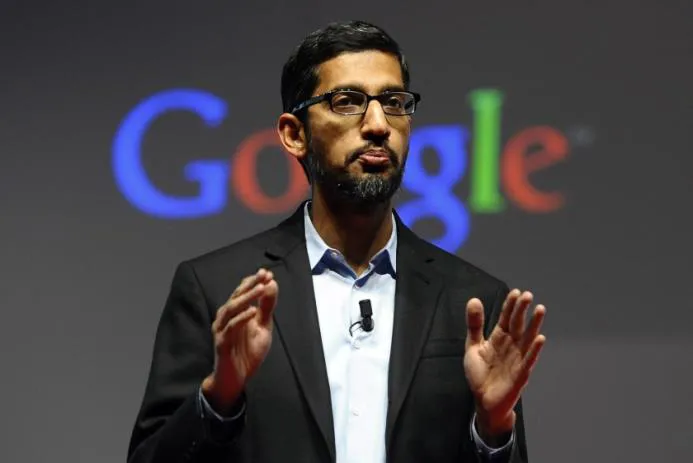 Sundar Pichai, CEO of Google, delivering a speech with Google logo in the background.