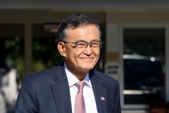 smiling-asian-american-man-navy-suit-glasses-us-flag-pin-professional-portrait